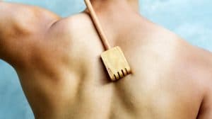 man scratching his back with wooden back scratcher